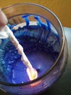 lit paper inserted into deep candle